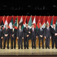 Members of the Council of Arab Ambassadors and Heads of Missions in Japan stand on stage as Prime Minister Shinzo Abe shakes hands with Dean of the Arab Diplomatic Corps Waleed Siam at the Imperial Hotel, Tokyo on April 4. | YOSHIAKI MIURA
