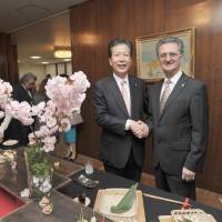 Romanian Ambassador Radu Serban (right) shakes hands  with Komeito leader Natsuo Yamaguchi during a cherry blossom viewing party at the embassy in Tokyo on March 30. | YOSHIAKI MIURA