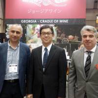 From left, Advisor to Chairman, State Department of Vine and Wine Giorgi Tevzadze, The Japan Times President Takeharu Tsutsumi and Georgian Ambassador Levan Tsintsadze pose in front of the Georgian wine booth following a seminar on Georgia\'s traditional Qvevri wine making at Wine &amp; Gourmet Japan 2016, at Tokyo Big Sight on April 13. | RINA HASEGAWA