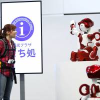 Hitachi Ltd. demonstrates how its humanoid customer service and guidance robot EMIEW3 can assist overseas tourists during an unveiling in Tokyo on Friday. The robot was developed to provide services and guidance in stores and at public facilities, Hitachi said. | REUTERS