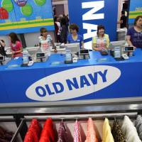 Employees wait for customers at the check-out counter of the Old Navy shop in Tokyo. Gap Inc. says the fashion brand is pulling out of Japan amid sluggish sales. | BLOOMBERG