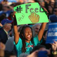 A supporter of Democratic presidential candidate Bernie Sanders displays a sign during a rally Saturday in National City, California. | AFP-JIJI