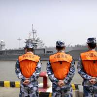 As the USS Blue Ridge arrives in Shanghai on May 6, three Chinese People\'s Liberation Army Navy soldiers stand and watch. | AP
