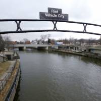 A sign over the Flint River in January calls Flint, Michigan, the Vehicle City. The state of Michigan will pay all Flint water bills in May to encourage the flushing of lead from old pipes and the recoating of plumbing with a corrosion chemical. To promote pipe flushing, Flint's May water bill to be put on state's tab