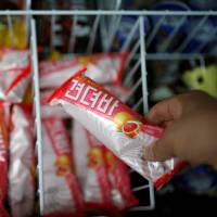 A clerk arranges Gyeondyo bars at a convenience store in Seoul on Friday. | REUTERS