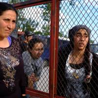 People who were sent out during a police operation to evacuate a makeshift camp at the Greek-Macedonian border near the village of Idomeni stand in front of a camp in the village of Oreokastro, Greece, Tuesday. | REUTERS