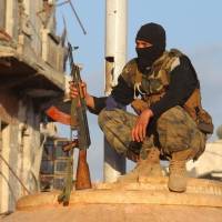 A member of the Nusra Front, al-Qaida\'s Syria wing, holds his weapon as he squats in the northwestern city of Ariha, Idlib province, in May 2015. | REUTERS