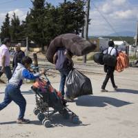 Migrants leave the camp in Idomeni, Greece, Thursday. Greek police continue an operation to evacuate the sprawling, makeshift Idomeni refugee camp on the Greek-Macedonian border. | AP