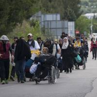 Migrants walk from the direction of the camp in Idomeni, near Evzoni, Greece, Wednesday. | AP