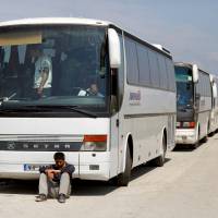 A migrant sits in front of a bus during a police operation to evacuate a migrants\' makeshift camp at the Greek-Macedonian border near the village of Idomeni Thursday. | REUTERS