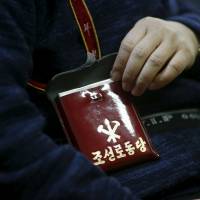 Seo Jae-pyoung, the secretary general of the association of the North Korean defectors, poses for a photograph while demonstrating the use of a Workers\' Party membership card holder during an interview in Seoul on April 22. | REUTERS