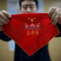 Seo Jae-pyoung, the secretary general of the association of the North Korean defectors, poses for a photograph while demonstrating the use of a cloth, which is used to wrap a Workers\' Party membership card in a holder, during an interview in Seoul on April 22. | REUTERS