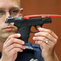 A police officer holds up the gun that George Zimmerman used to kill Trayvon Martin during Zimmerman’s murder trial in Seminole circuit court in Sanford, Florida, in June 2013. Top U.S. auctioneers refused to sell gun from Trayvon Martin shooting