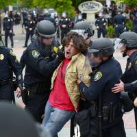 A protester who refused to comply with San Diego police officers in Gaslamp Quarter is taken into custody Friday. | AP