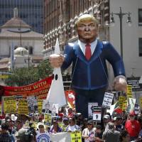 People march with an inflatable effigy of Republican presidential candidate Donald Trump during an immigrant rights May Day rally in Los Angeles on Sunday. Trump unfazed by rally violence, sticks with woman's card jab at Clinton