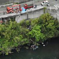 Rescue personnel examine the site where a van carrying construction workers plunged into a reservoir in Kawachinagano, Osaka Prefecture, on Sunday. | KYODO