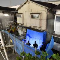 Police investigate an apartment building in Amagasaki, Hyogo Prefecture, Thursday after a resident was arrested on suspicion of stabbing a woman upstairs and her daughter, who subsequently died. | KYODO