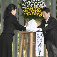 Welfare minister Yasuhisa Shiozaki transfers the remains of an unidentified soldier from World War II to an official at Chidorigafuchi National Cemetery in Tokyo on Monday. | KYODO