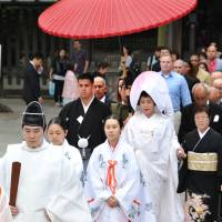 Jonathan Madrid, 24, and Nao Sasaki, 30, are led by priests to the wedding hall at Tokyo\'s Meiji Jingu on Saturday. | YOSHIAKI MIURA