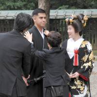 Staff of Tokyo\'s Meiji Jingu shrine adjust Jonathan Madrid\'s kimono as his bride, Nao Sasaki, looks on. | YOSHIAKI MIURA