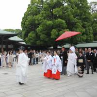 Onlookers observe the wedding procession of Jonathan Madrid and Nao Sasaki at Meiji Jingu in Tokyo on Saturday. | YOSHIAKI MIURA