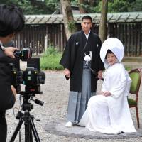 Jonathan Madrid and Nao Sasaki have their picture taken after their wedding ceremony at Meiji Jingu in Tokyo on Saturday. | YOSHIAKI MIURA