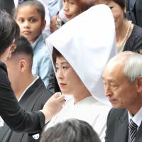 A staffer at Tokyo\'s Meiji Jingu shrine gives a touch of powder to Nao Sasaki\'s makeup during a group photo session after their wedding Saturday. | YOSHIAKI MIURA