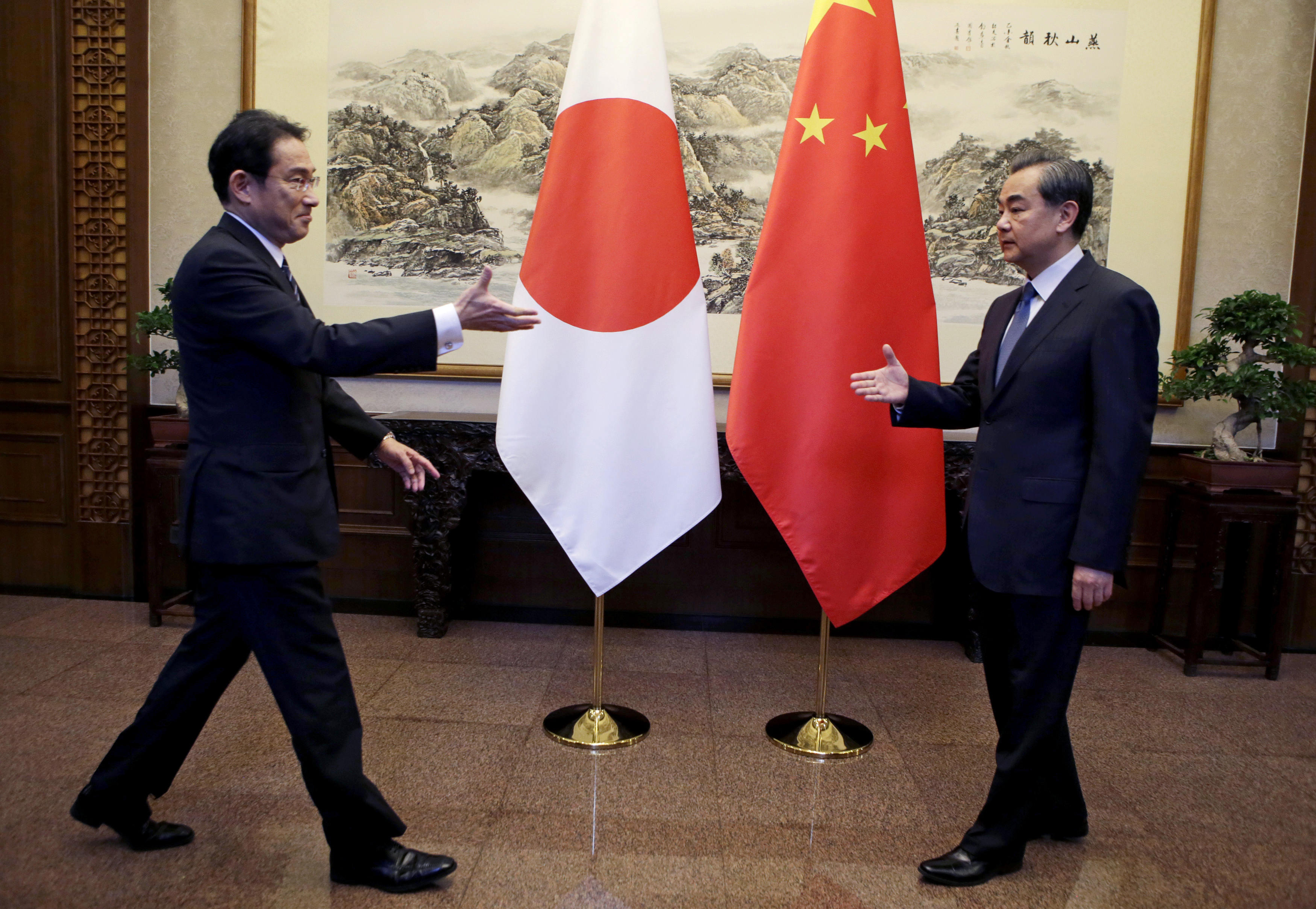 Foreign Minister Fumio Kishida (left) reaches out to shake hands with his Chinese counterpart, Wang Yi, during a meeting at Diaoyutai State Guesthouse in Beijing on Saturday.  pool / ap | KYODO