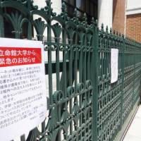 A gate to one of Ritsumeikan University\'s campuses in Kyoto on Saturday bears a sign saying it is closed due to a bomb threat. | KYODO