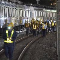 Workers repair a Tobu Tojo Line train Wednesday night that derailed earlier in the day in Tokyo\'s Itabashi Ward. | KYODO