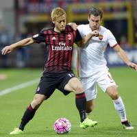 AC Milan\'s Keisuke Honda (left) holds off a Roma defender during Serie A action on Saturday. | KYODO