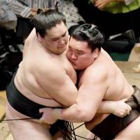 Yokozuna Hakuho (right) outmuscles ozeki Terunofuji during their Summer Grand Sumo Tournament match on Tuesday at Ryogoku Kokugikan. | KYODO