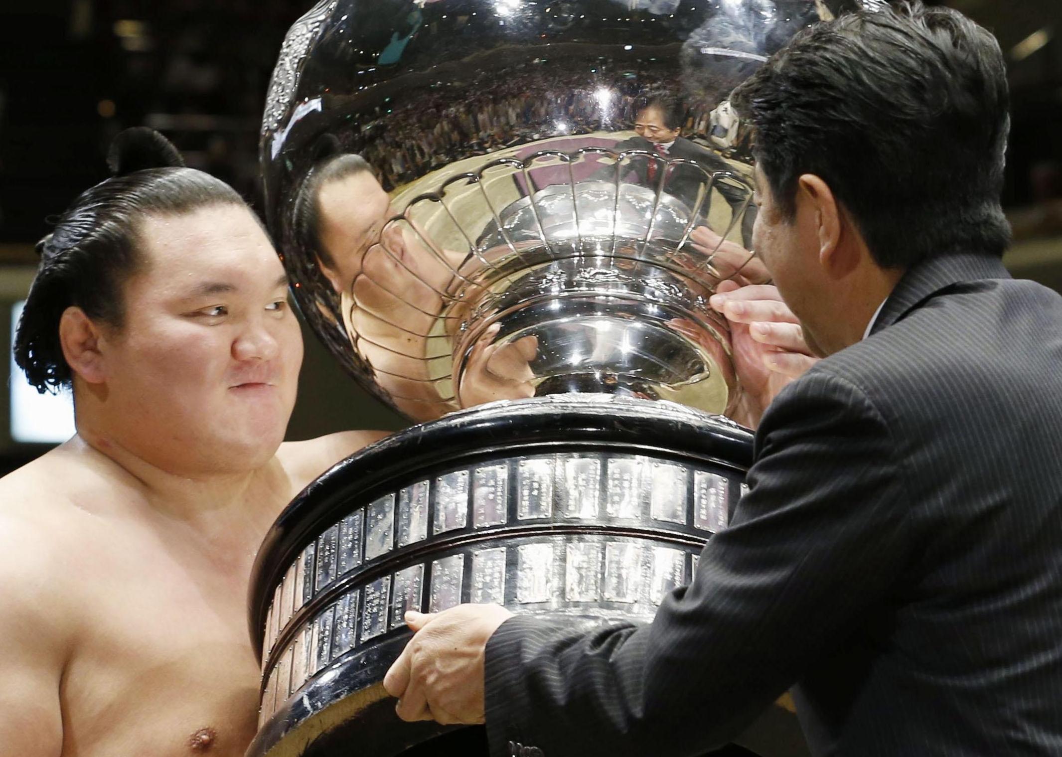Yokozuna Hakuho receives the trophy from Prime Minister Shinzo Abe on Sunday after winning the Summer Grand Sumo Tournament. | KYODO