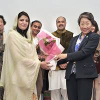 Zaib Malik (left), wife of Shehzad Ahmed Khan, commercial counsellor of the Pakistan Embassy, receives a bouquet from Haruko Komura, president of the Asia-Pacific Ladies Friendship Society (ALFS), on April 28, during the society\'s Spring Cultural Event 2016 at the Pakistan Embassy. Standing to the left of Komura is Farukh Amil, ambassador of the Islamic Republic of Pakistan. | YOSHIAKI MIURA