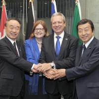 Viorel Isticioaia-Budura (second from right), the ambassador of the European Union, and his wife Tatiana (second from left) shake hands with State Minister for Internal Affairs and Communications Masatada Tsuchiya (left) and Kenji Kosaka, chairman of the EU-Japan Parliamentary League of Friendship and House of Councillors member at a reception to celebrate \"Europe Day\" at the Delegation of the European Union\'s Europa House in Tokyo on May 10. | YOSHIAKI MIURA
