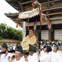 Fumon Sagawa, 65, is carried during a ceremony Monday marking his inauguration as the 222nd chief priest of Todaiji Temple in the city of Nara. The building to the rear is the Great Buddha Hall, which houses the world\'s largest bronze statue of Buddha. | KYODO