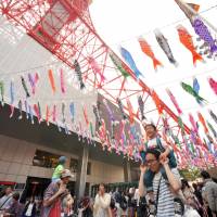 Visitors to Tokyo Tower walk under hundreds of koinobori (carp streamers) during a special event Sunday ahead of Children\'s Day, which falls on Thursday. | YOSHIAKI MIURA
