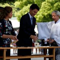 Canadian Prime Minister Justin Trudeau and his wife, Sophie Gregoire-Trudeau, are escorted by a Shinto priest as they write messages on a wooden prayer tablet at Meiji Shrine in Tokyo on Tuesday ahead of the Ise-Shima Group of Seven summit. | REUTERS