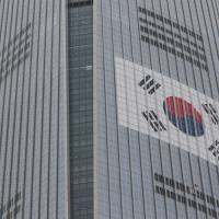 The South Korean national flag is displayed on the facade of Lotte Corp.\'s World Tower as it was being built in Seoul in December. Lotte Holdings Co. shareholders have voted to leave Lotte Group Chairman Shin Dong-bin in his post of director of the holding company. | BLOOMBERG