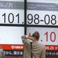 Pedestrians pass an electronic stock prices board at a securities firm in Tokyo on Tuesday. | AP