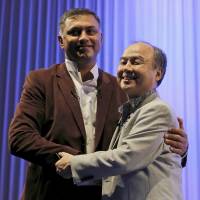 SoftBank Group Corp. Chairman and CEO Masayoshi Son (right) and President and COO Nikesh Arora shake hands at a lecture at the SoftBank Academia in Tokyo last October. | REUTERS