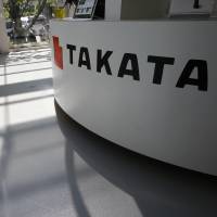 Visitors walk by a Takata Corp. display at an automaker\'s showroom in Tokyo on May 4. | AP