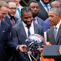 U.S. President Barack Obama receives a signed helmet from Denver Broncos quarterback Peyton Manning (left) as Obama welcomes the Broncos for a reception in honor of their NFL Super Bowl football championship, in the Rose Garden of the White House in Washington on Monday. | REUTERS