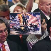 A supporter of Republican U.S. presidential candidate Donald Trump holds up a painting of him during a rally in Dallas on Thursday. | AP