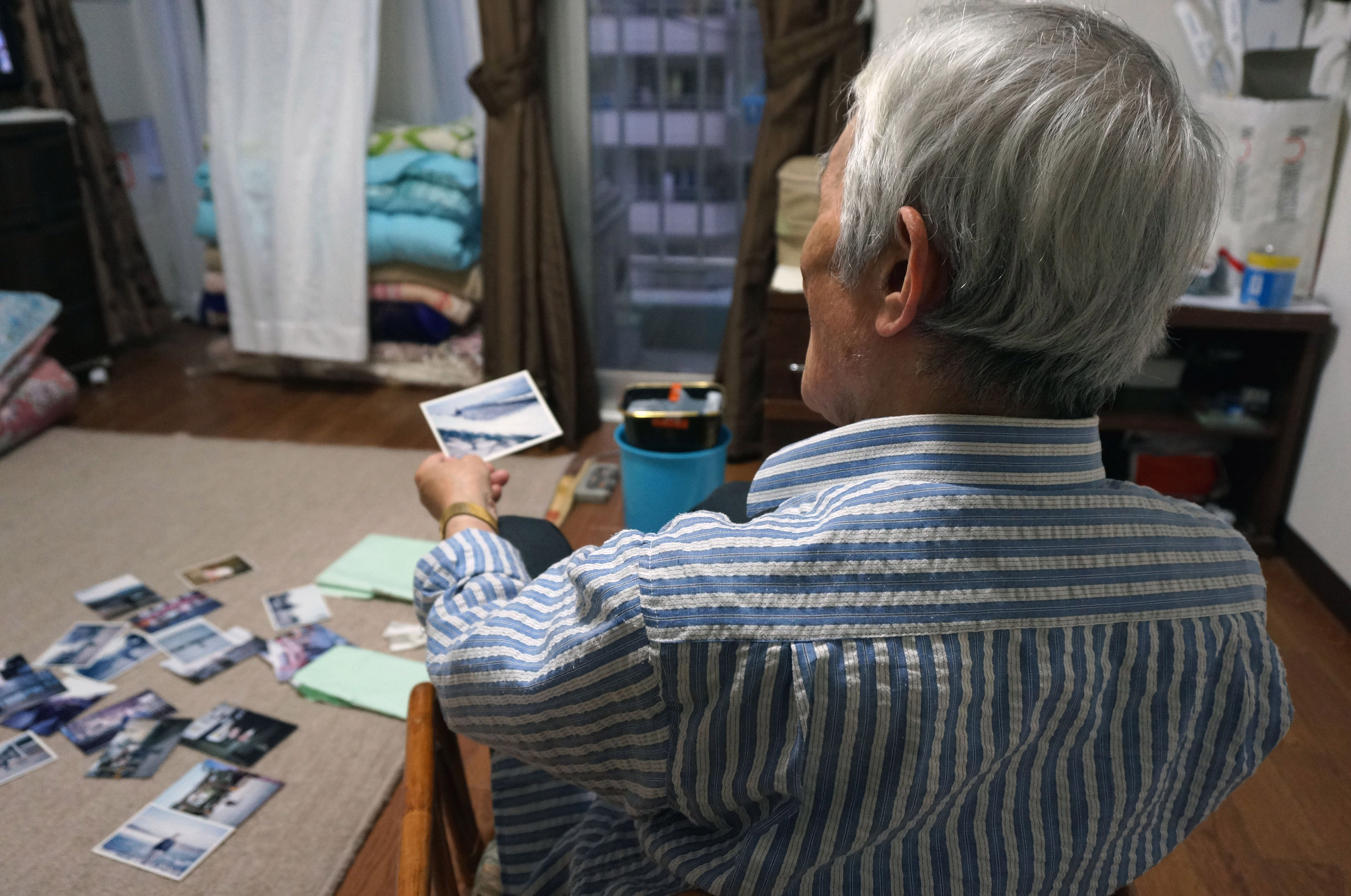 An elderly man living on welfare displays photos from his youth at his home in Tokyo's Shinjuku Ward in May. | KYODO