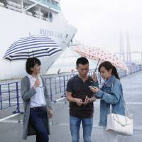 University students in Aichi Prefecture chat with a crew member (center) of a cruise ship moored at the port of Nagoya after showing him around the city recently. | CHUNICHI SHIMBUN