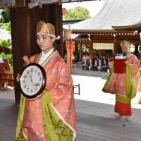 Women clad in ancient Japanese court dress walk holding clocks during an annual clock festival on Friday at Omi Shrine in Otsu, Shiga Prefecture. Emperor Tenji (626-672), said to be the founding father of the clock time system in Japan, is enshrined there as its deity. | KYODO