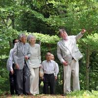 Emperor Akihito and Empress Michiko listen to C.W. Nicol as they walk together in Afan Woodland in Shinano, Nagano Prefecture, on Monday. | POOL / KYODO