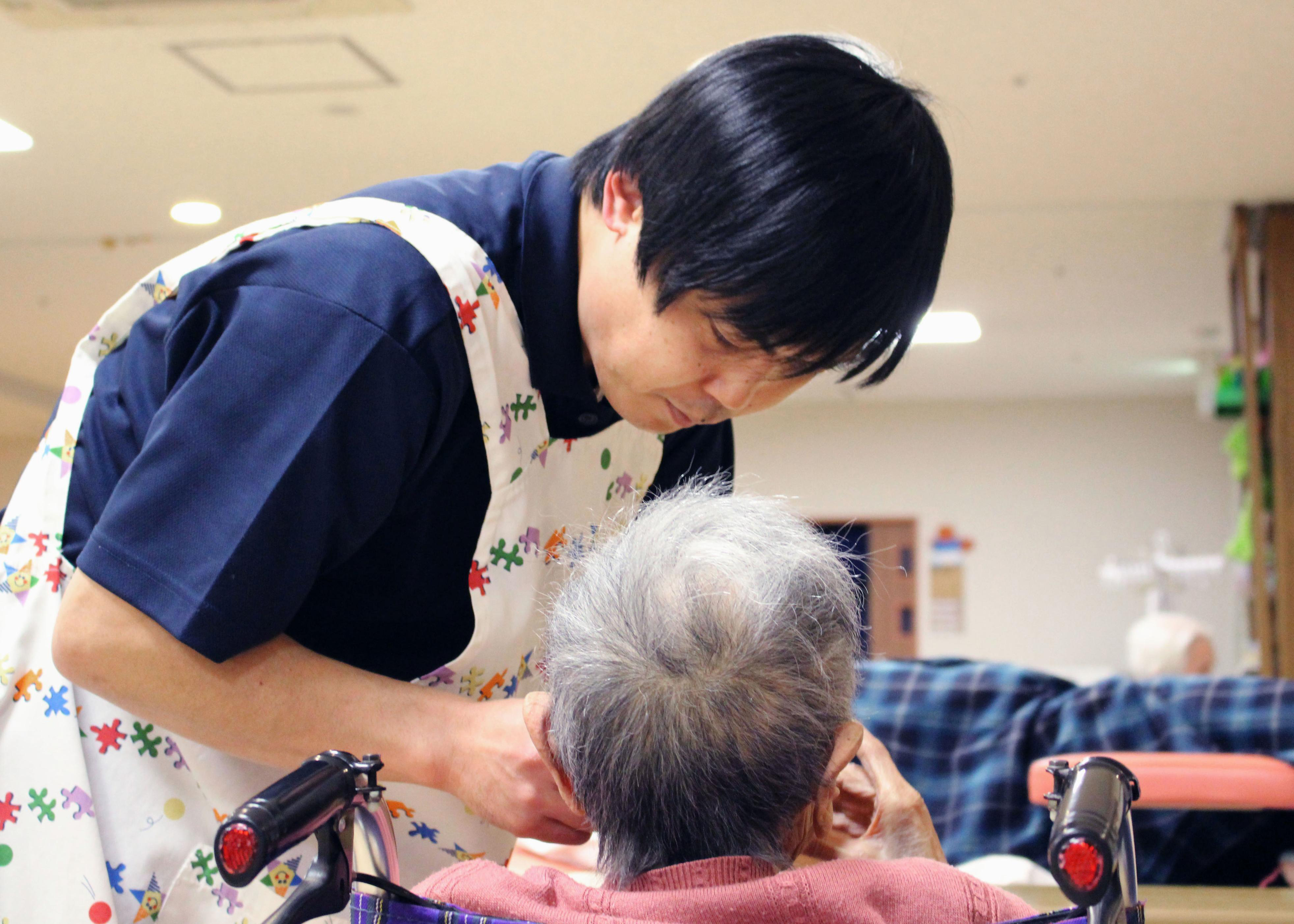 A nursing care worker helps a senior eat at a nursing care facility in Tokyo in March. Japan's care-worker shortage is becoming increasingly serious. | KYODO