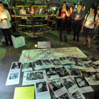 Photos of victims of Sunday\'s mass shooting in Orlando, Florida, are displayed at a candlelight vigil Tuesday evening in Shinjuku Ni-chome, Tokyo\'s main gay district. | YOSHIAKI MIURA